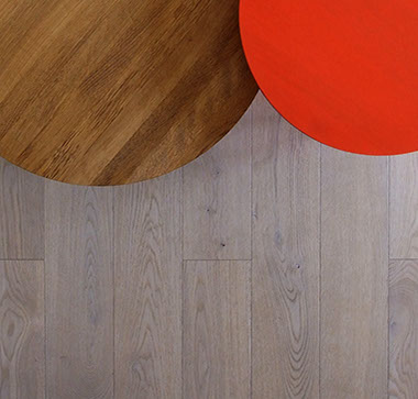 Photographie présentant un détail de 2 tables basse sur un parquet en chêne massif. Tables Bella de Hay, en bois rouge et chêne naturel