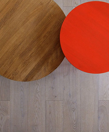Photographie présentant un détail de 2 tables basse sur un parquet en chêne massif. Tables Bella de Hay, en bois rouge et chêne naturel