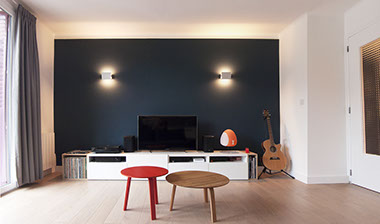 Salon avec un mur bleu sombre Farrow and Ball et 2 appliques 1962 de Charlotte Perriand. Parquet en chêne massif. 2 tables basse Bella de Hay. 