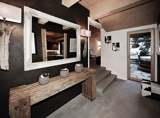 Hall d'entrée du chatet avec grand miroir au dessus d'une console en chêne. Accés vers cuisine, pièces de vie et jacuzzi extérieur.