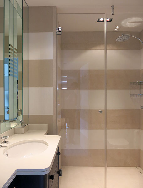 Salle de bains avec grande douche et paroi de verre. Meuble lavabo avec tablette en pierre et grand miroir.