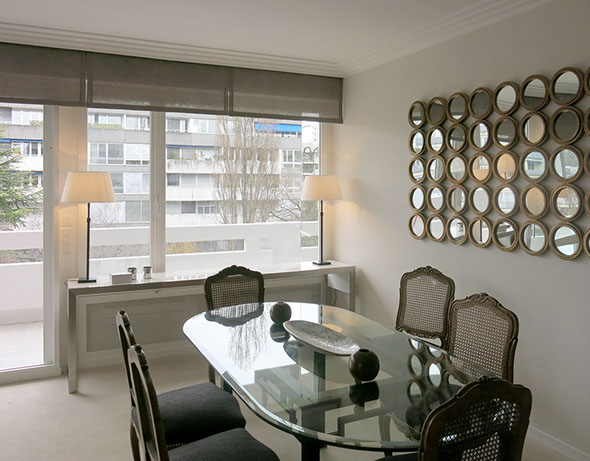 Table à manger en verre, grande console devant les fenêtre et assortiment de miroirs au mur.